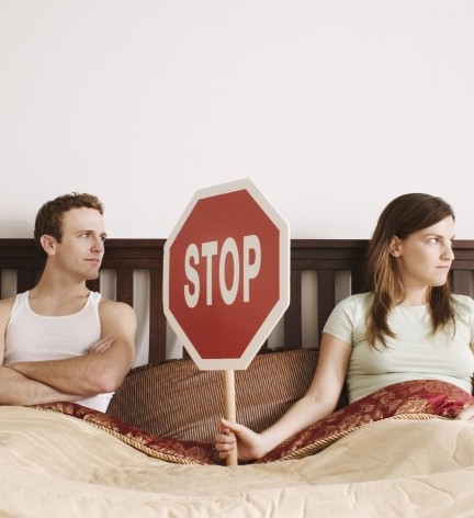 Couple holding stop sign in bed