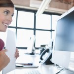 Young woman working on computer and listening to music in office
